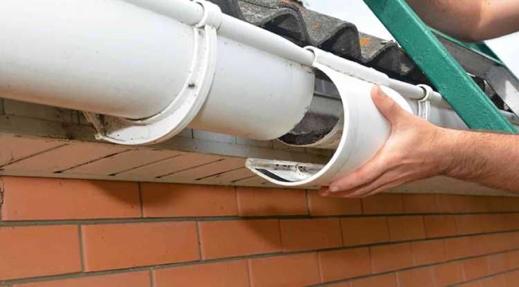 A person’s hand installs a white gutter connector on a home in Huntsville, AL by LJ Roofing