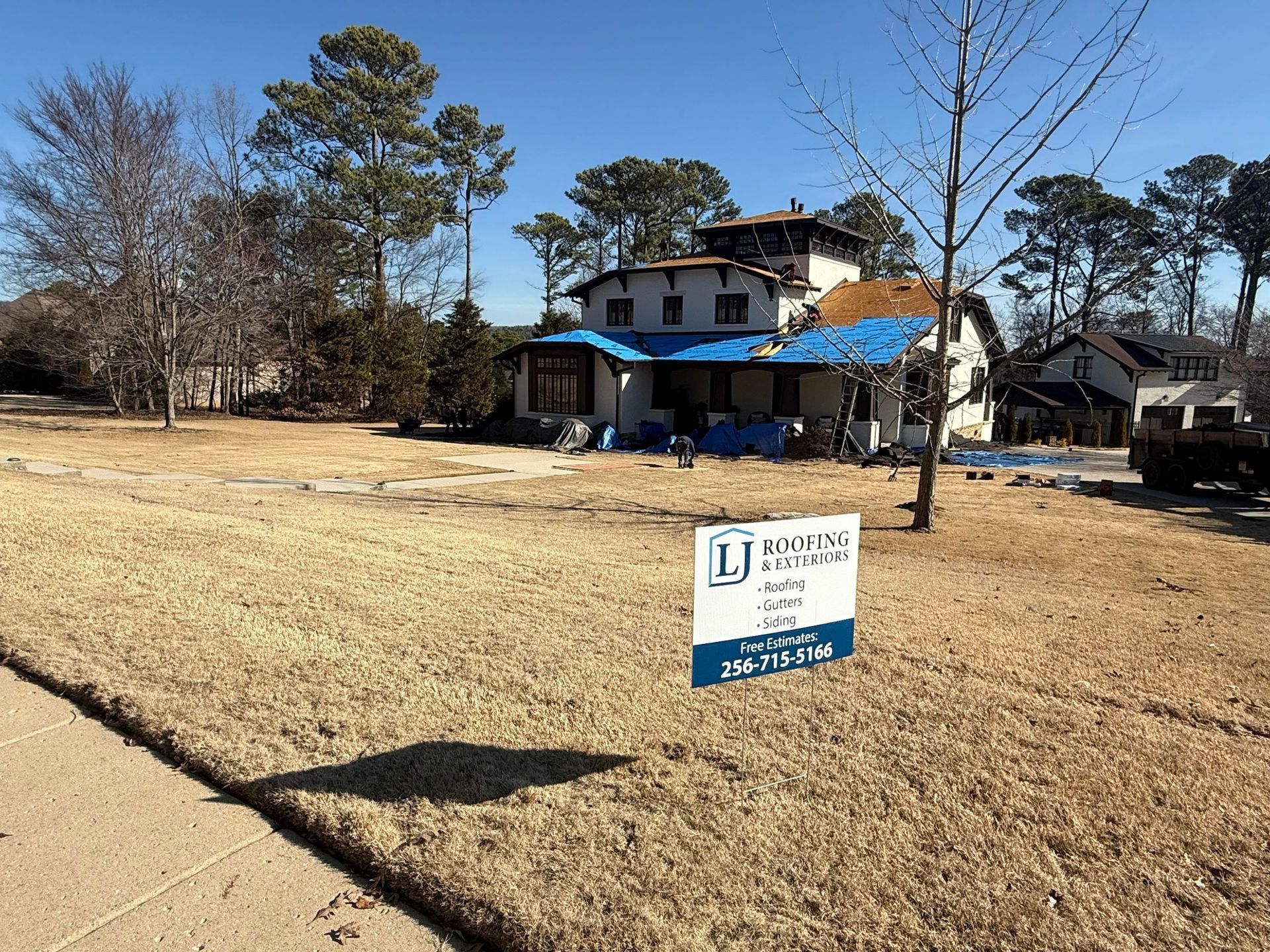 A residential home under construction with blue tarps on its roof, in Huntsville AL by LJ Roofing