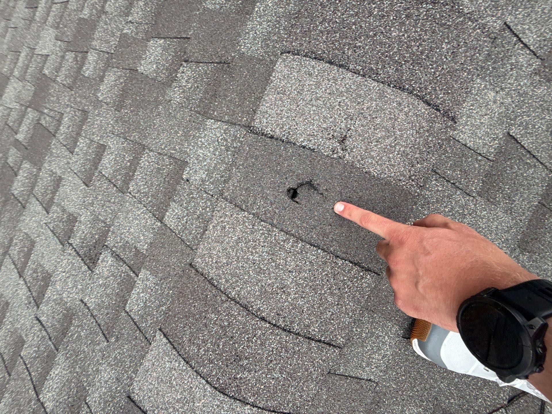 Storm damage on grey asphalt roof shingle on a home in Huntsville, AL by LJ Roofing