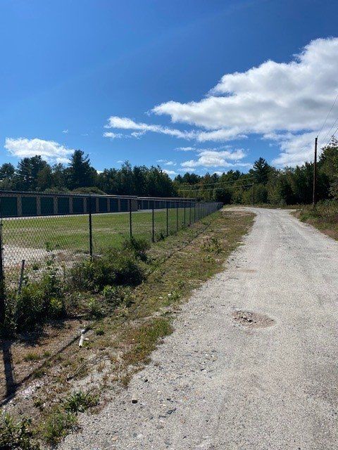 a dirt road with a fence along the side of it
