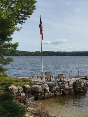 an american flag is flying over a lake with a dock in the foreground .
