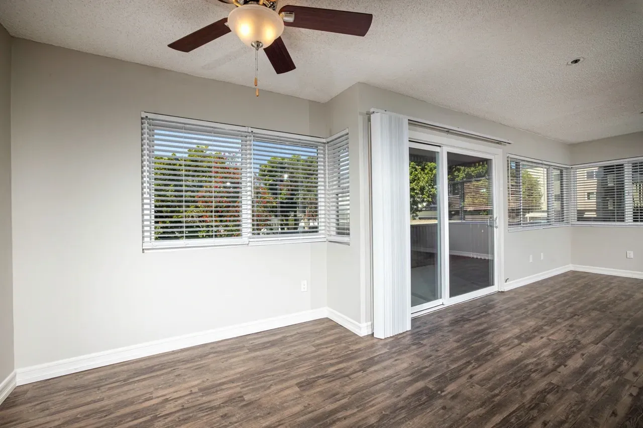 Bright and airy living room with large windows and a ceiling fan.