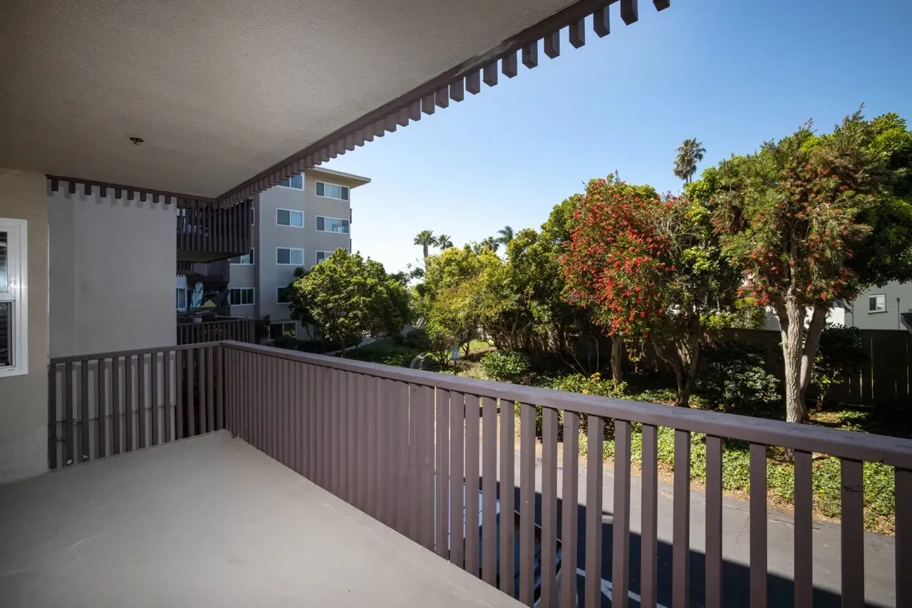 Balcony view of apartment buildings and lush greenery.
