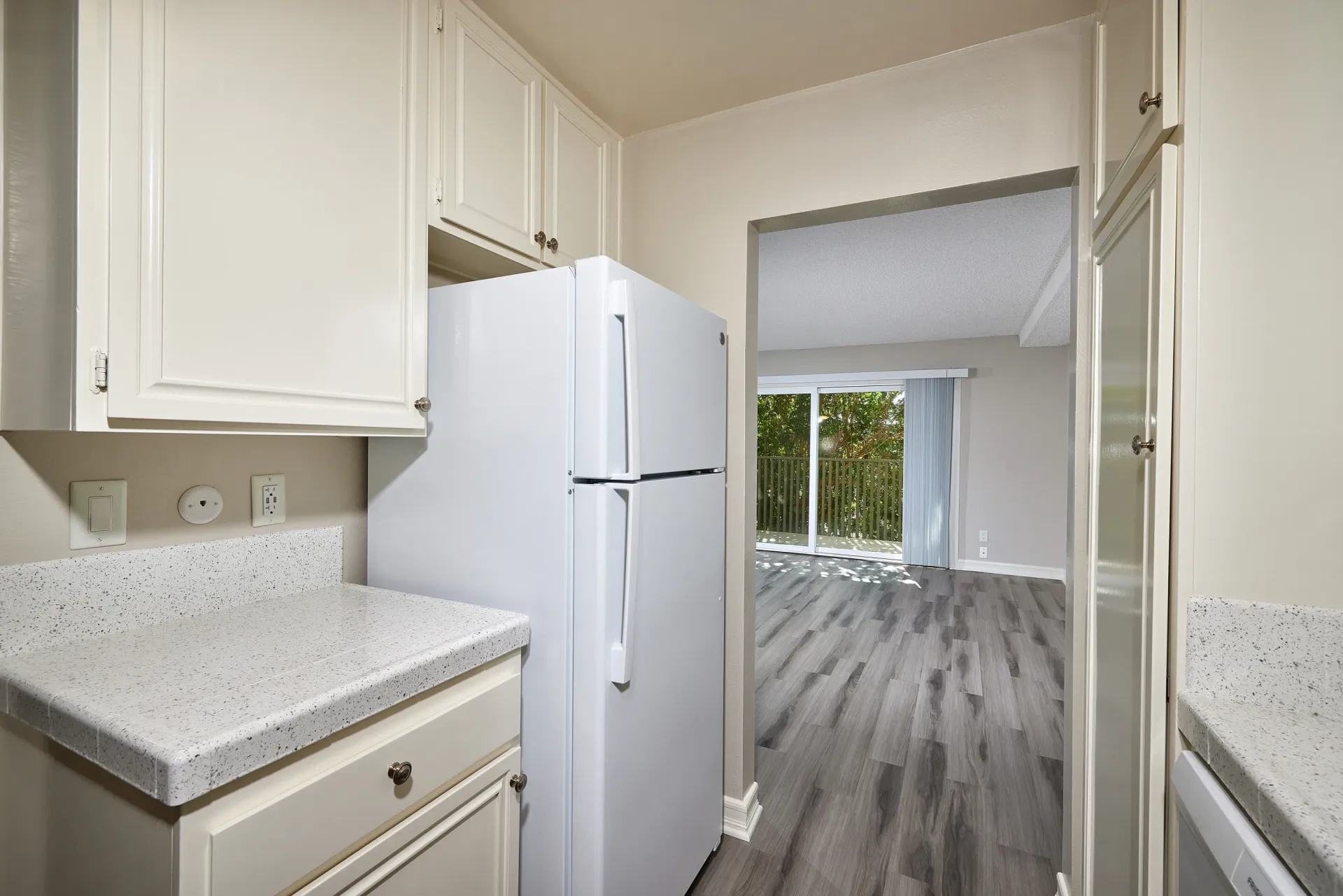 Kitchen with white cabinets, speckled countertops, and a white refrigerator.