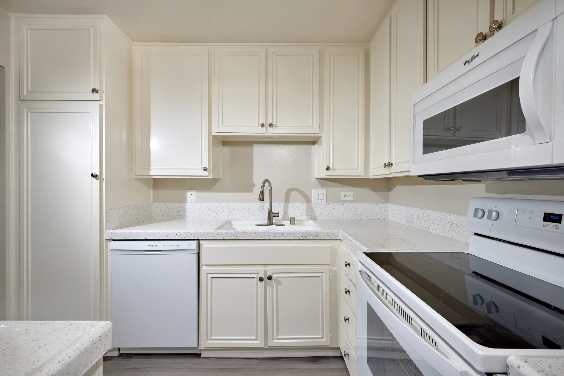Kitchen with white cabinets, granite countertops, white appliances including a microwave, stove, and dishwasher.
