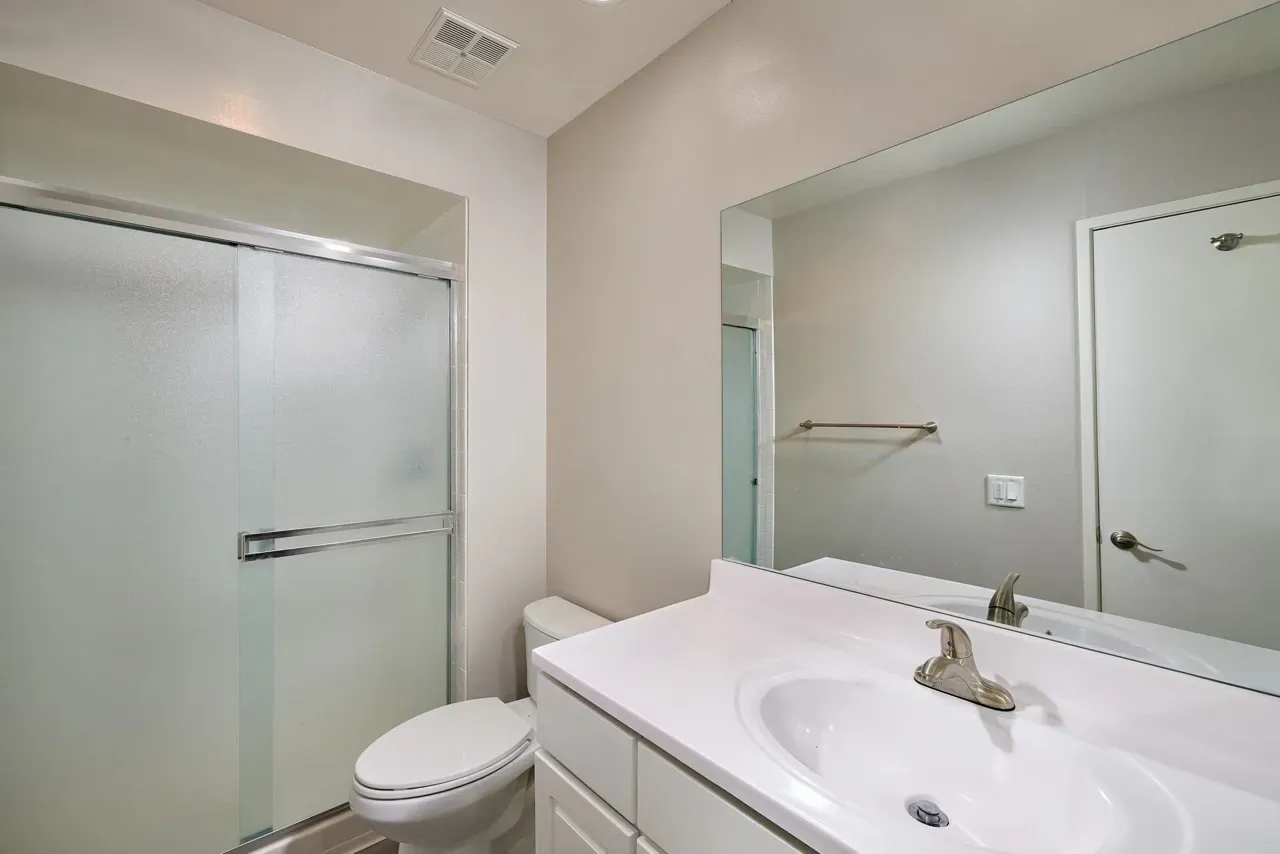 Bathroom with a vanity, sink, toilet, and shower.