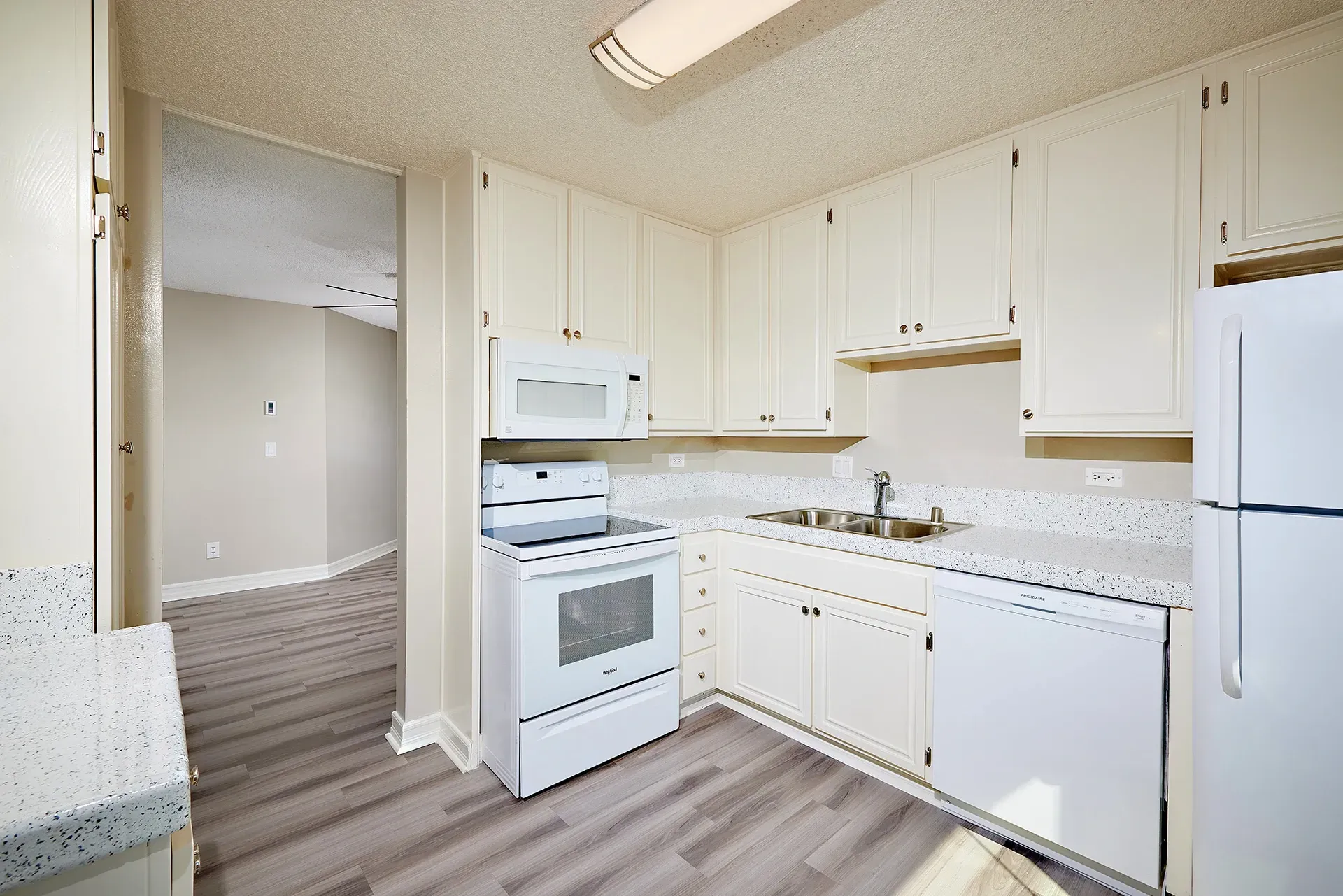 White kitchen with white cabinets, oven, microwave, dishwasher, and refrigerator.