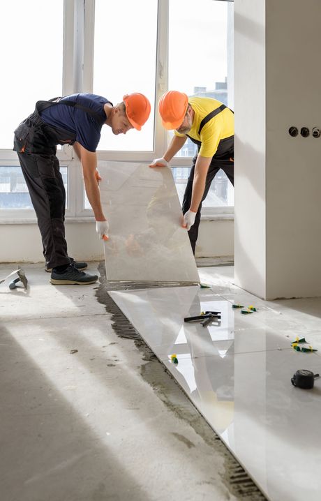 Two men are installing a tile floor in a room.