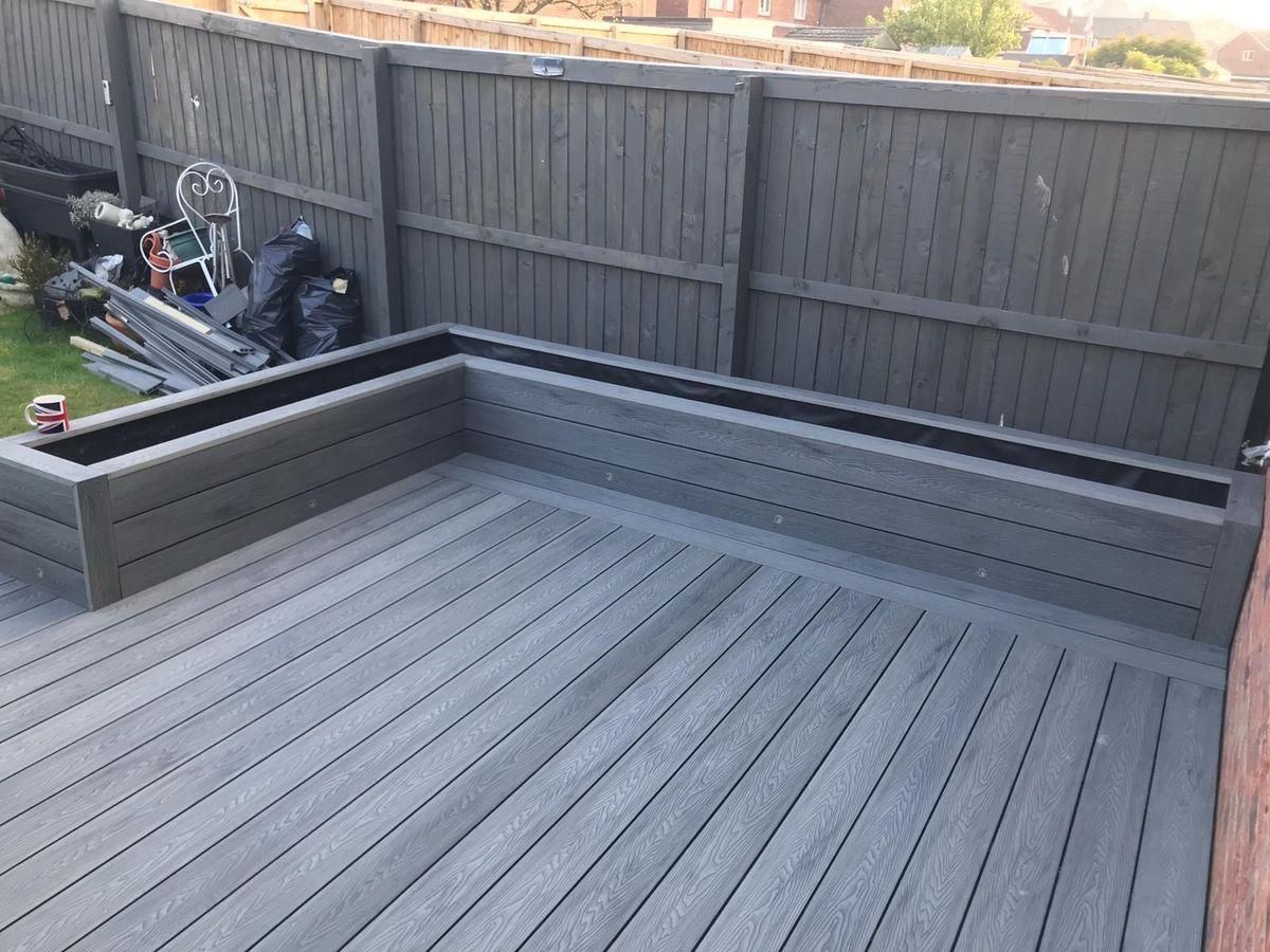 Gray composite deck with matching planters and a gray wooden fence.