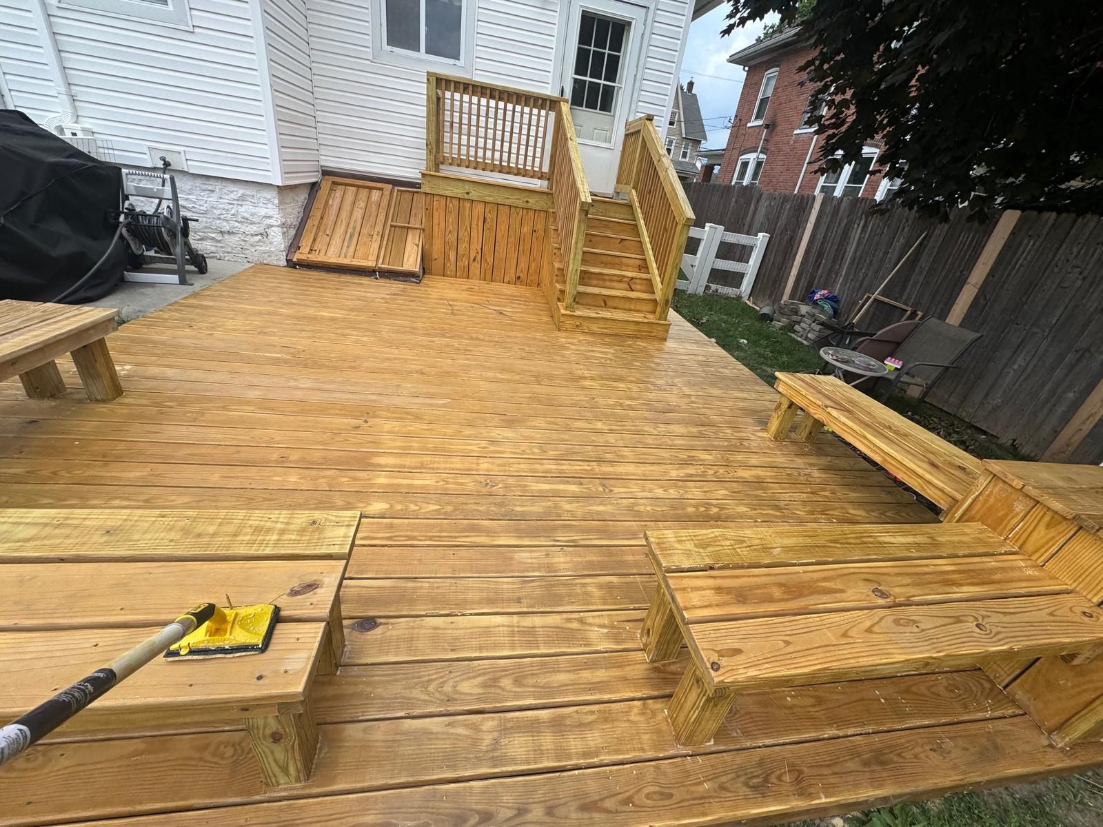 Wooden deck frame partially constructed next to a brick building.