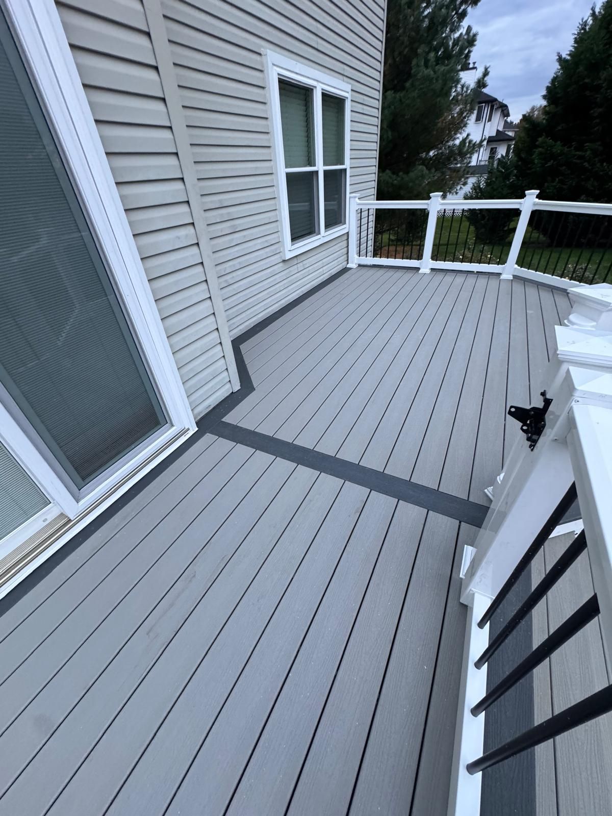 Gray composite deck with white railing, next to a house with light gray siding.