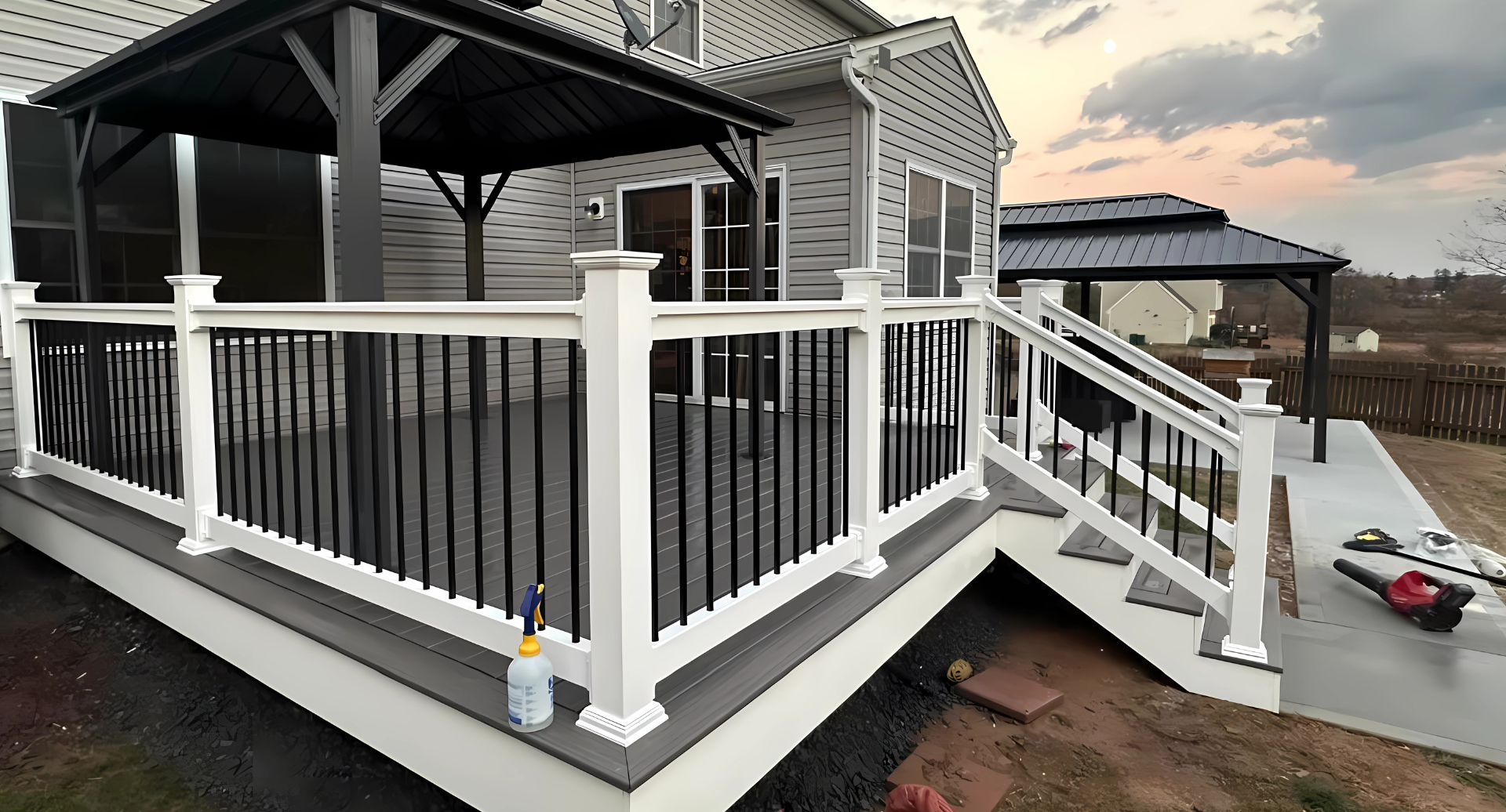 A composite deck with black railing and white posts leads to a covered gazebo.