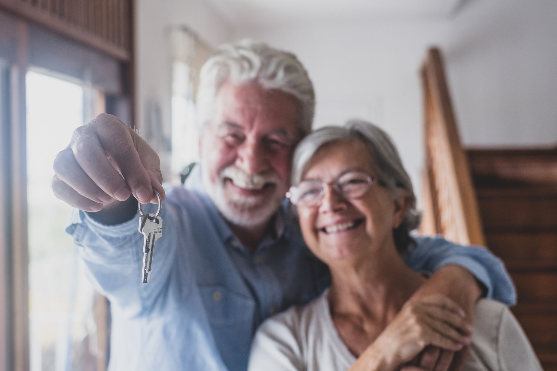 Happy aged woman and man holding key for new senior housing.