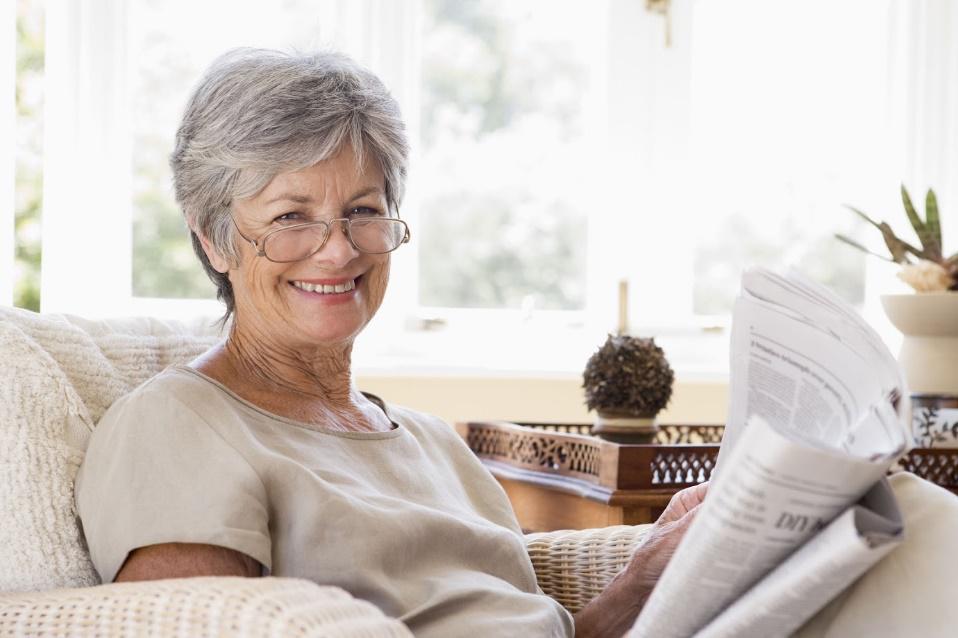 Senior Woman Reading Newspapers — Peoria, IL — Robert Cottingham Property Management Co