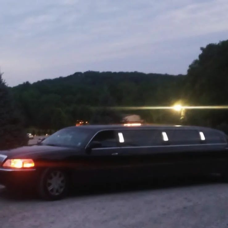 A black limousine is parked in a parking lot at night