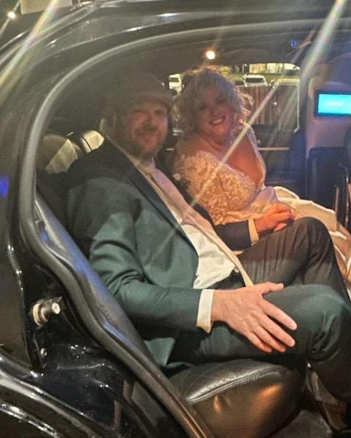 A man and a woman are sitting in the back seat of a car