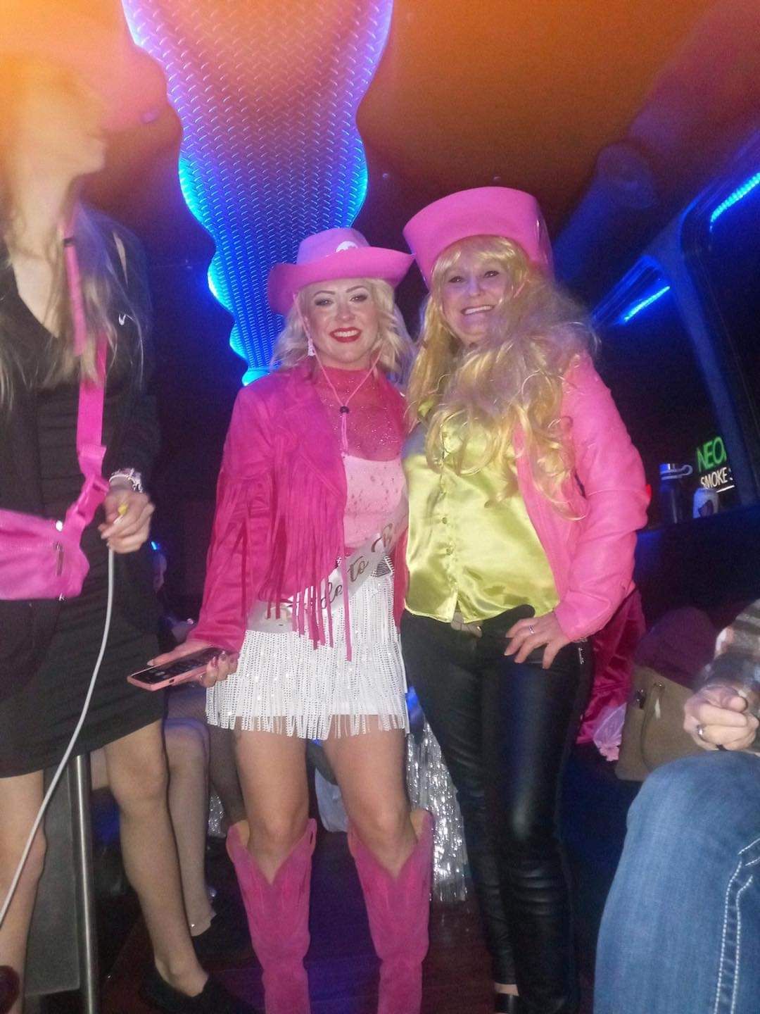 A woman in a pink cowboy hat is standing next to another woman
