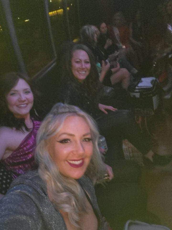 A group of women are posing for a selfie in a dark room.