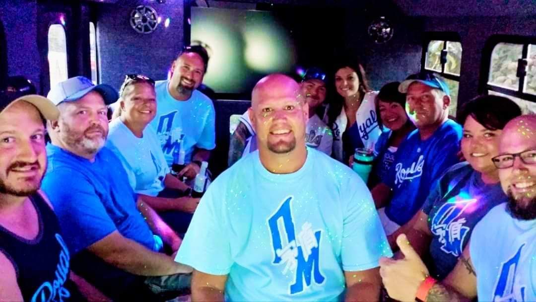A group of people wearing blue shirts are sitting around a table.