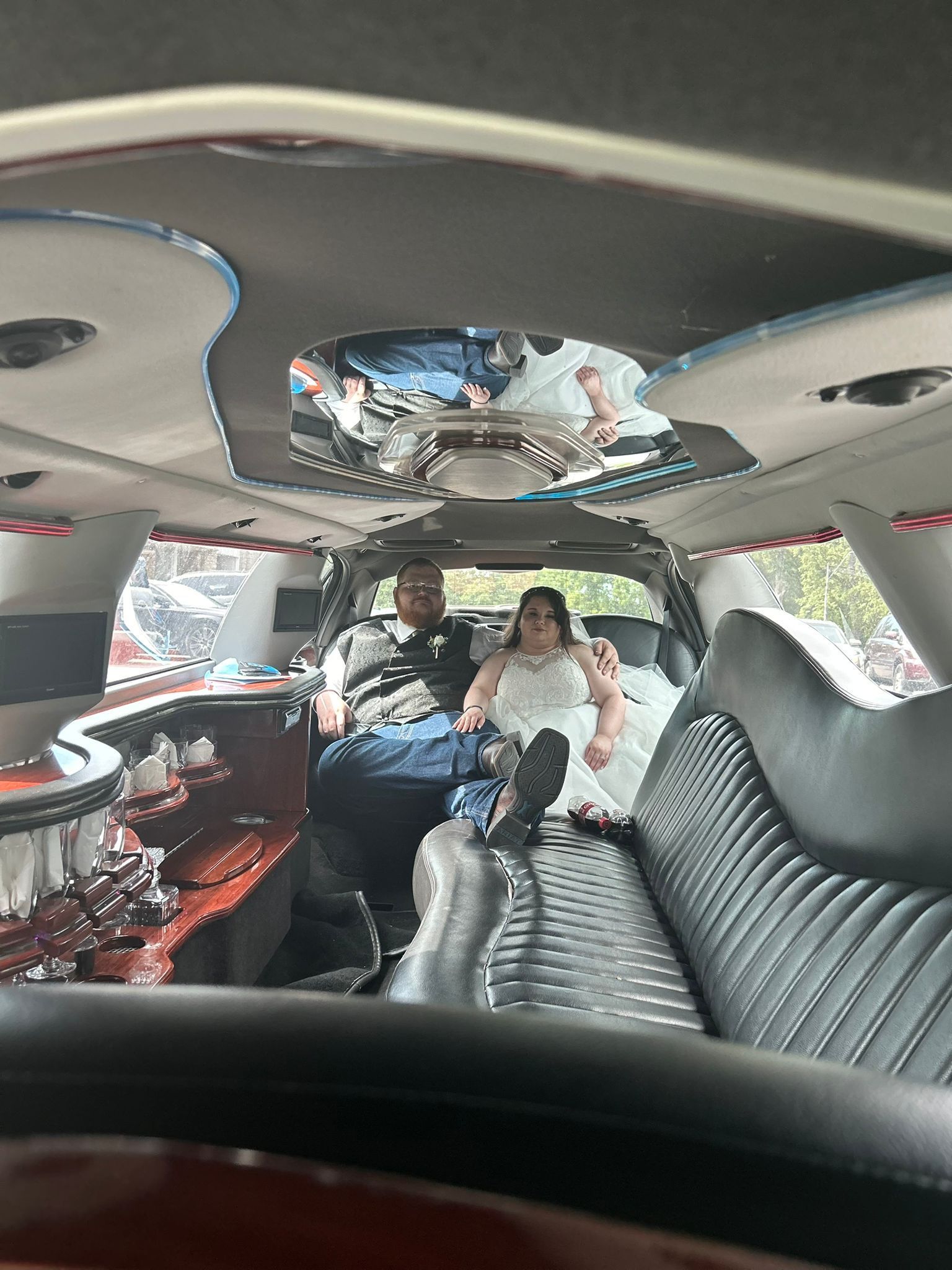 A bride and groom are sitting in the back seat of a limousine.