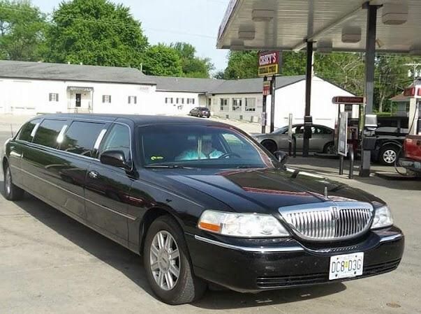 A black limousine is parked in front of a gas station