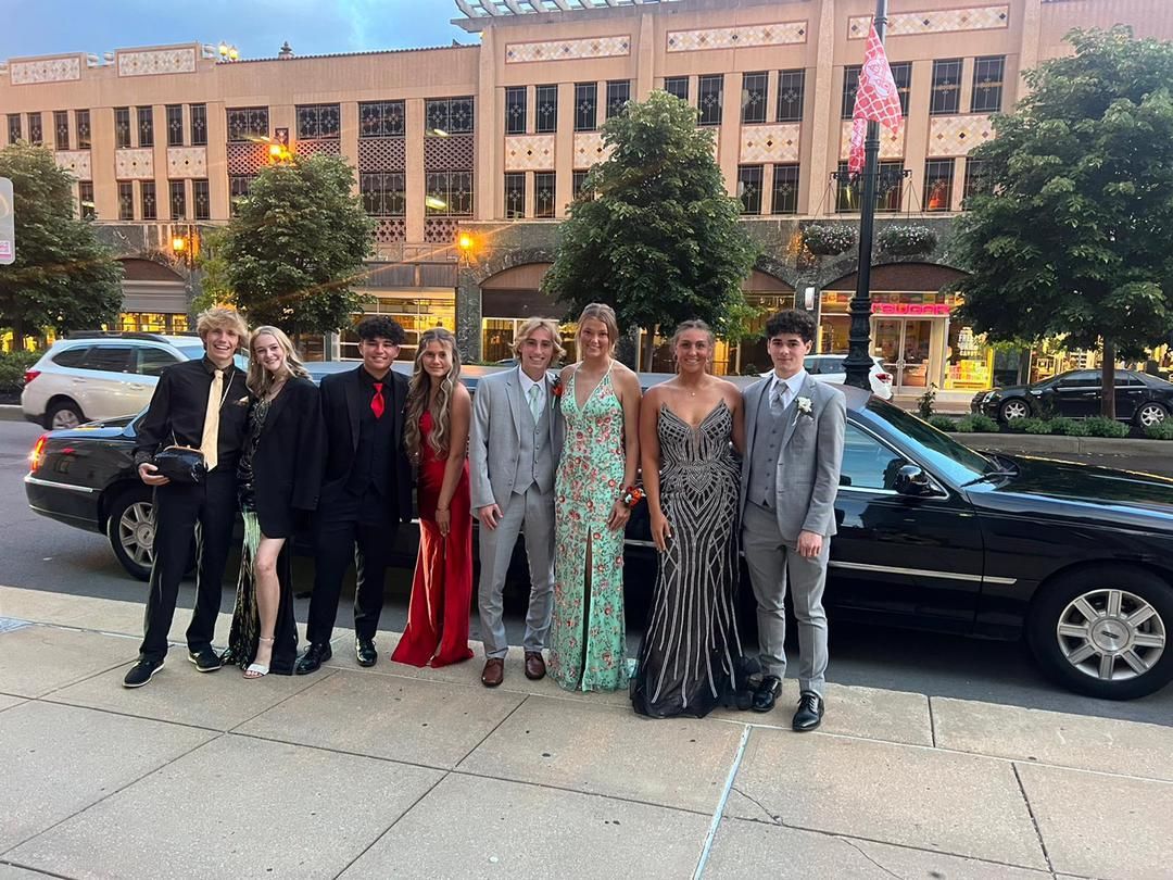 A group of people are posing for a picture in front of a limousine.