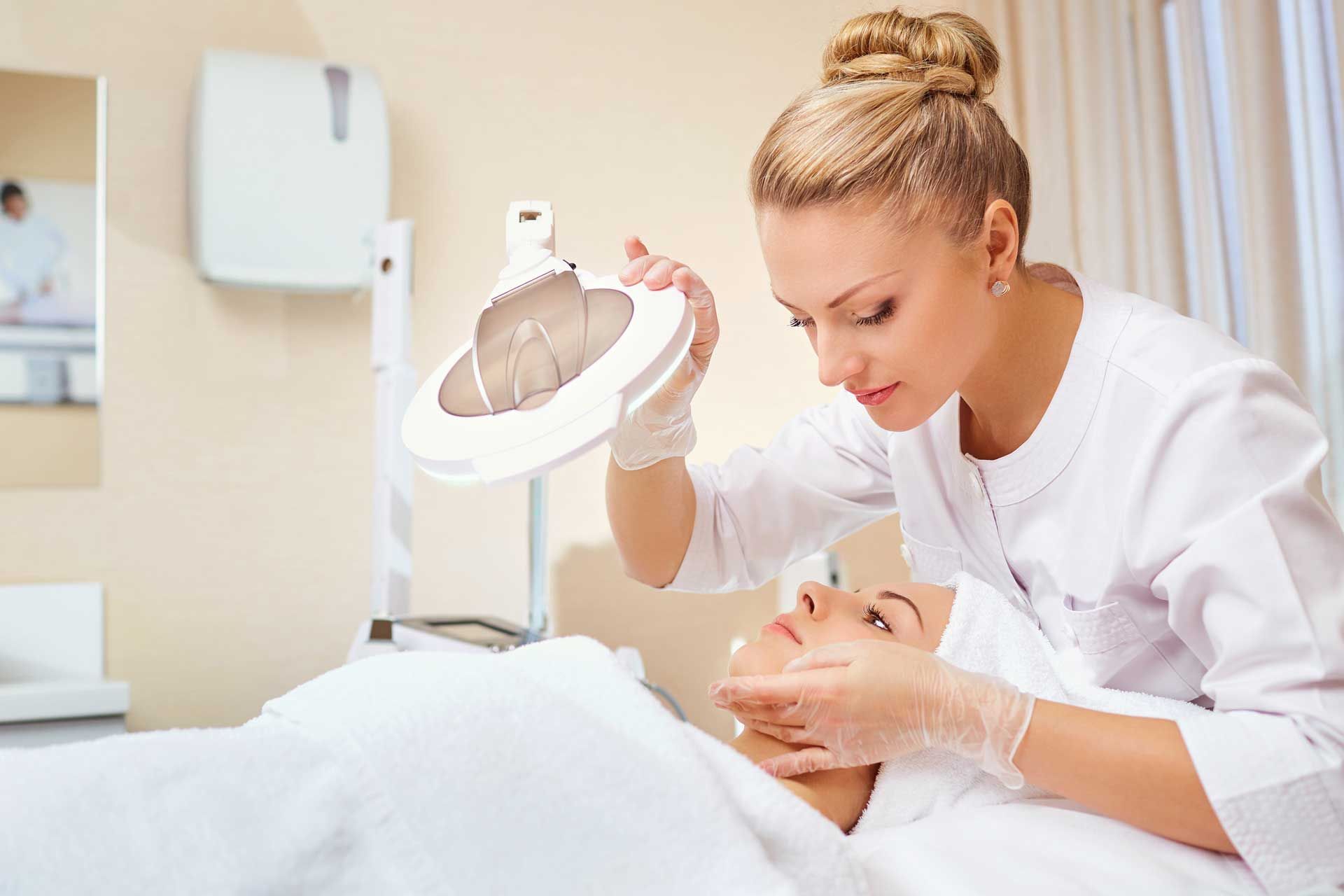 A woman is looking at a woman 's face with a facial device.