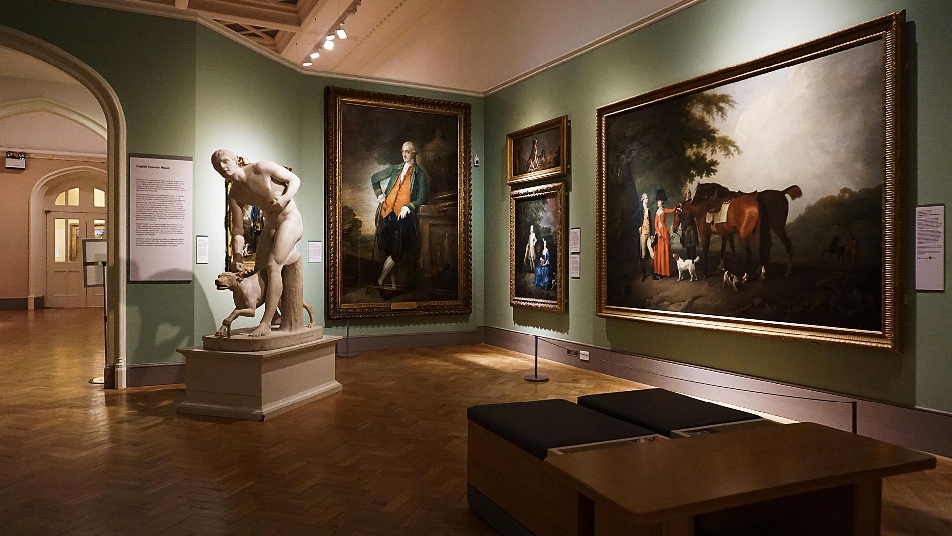 Museum gallery: statues, paintings, bench, and arched doorway. Green walls, wood floor. SPATIAL FINE ARTS