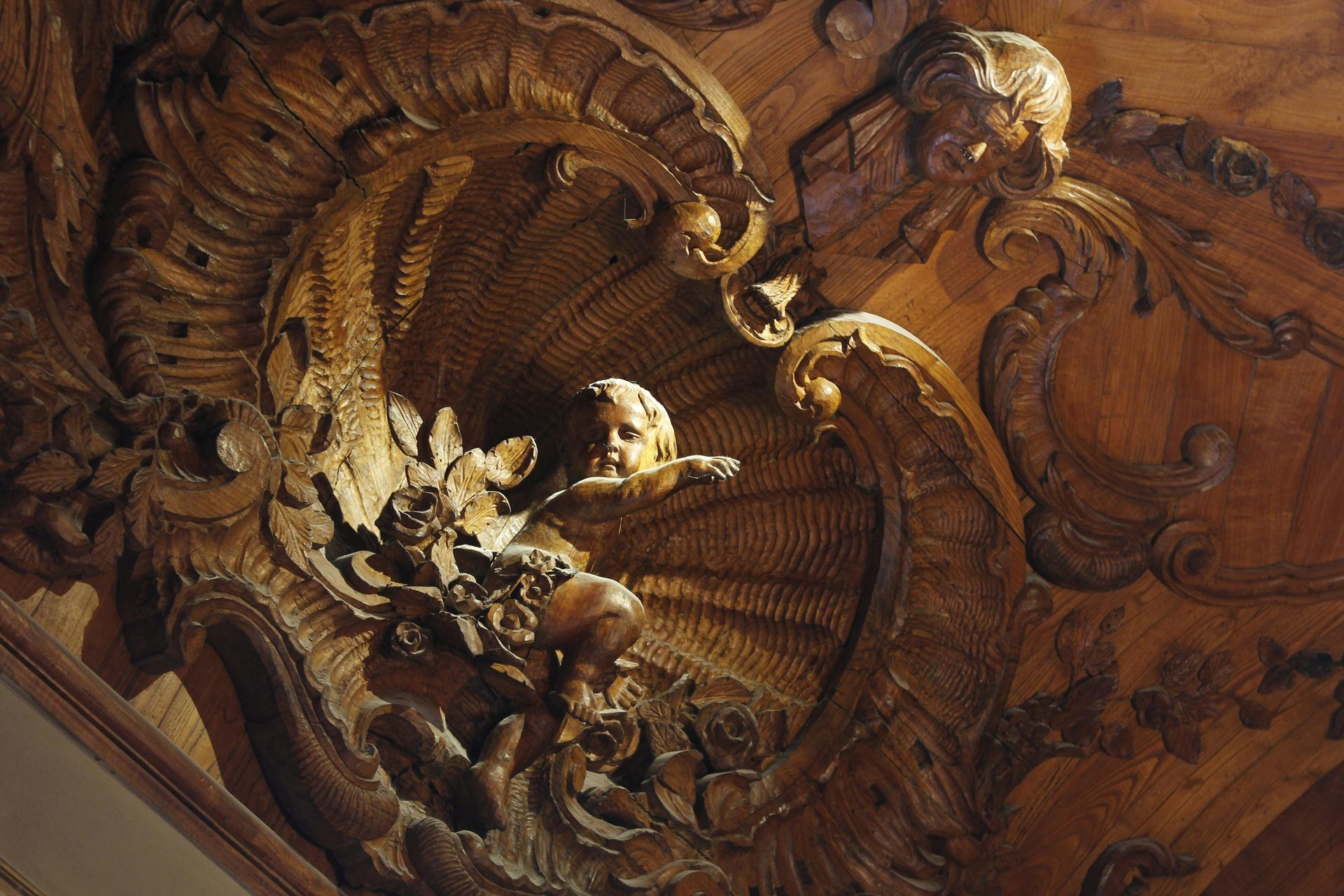Ornate carved wooden ceiling with a cherub figure. SPATIAL FINE ARTS