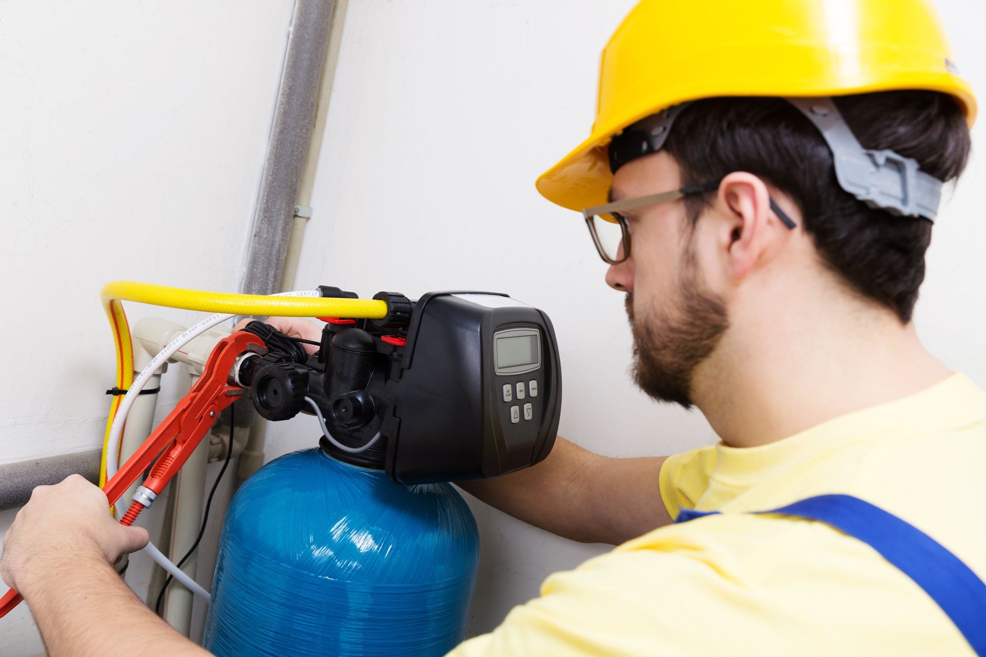 A man wearing a hard hat is working on a water filter.