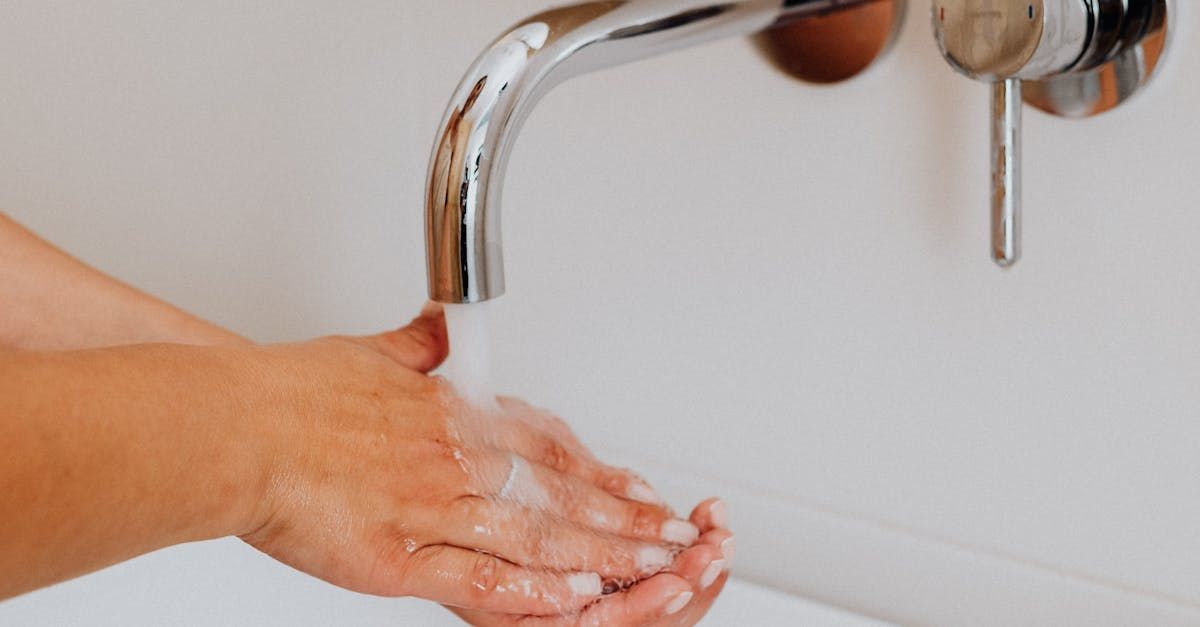 A person is washing their hands under a faucet in a bathroom.