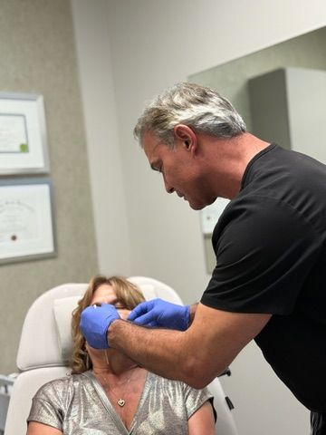 Doctor in blue gloves examining patient's face. Office setting.