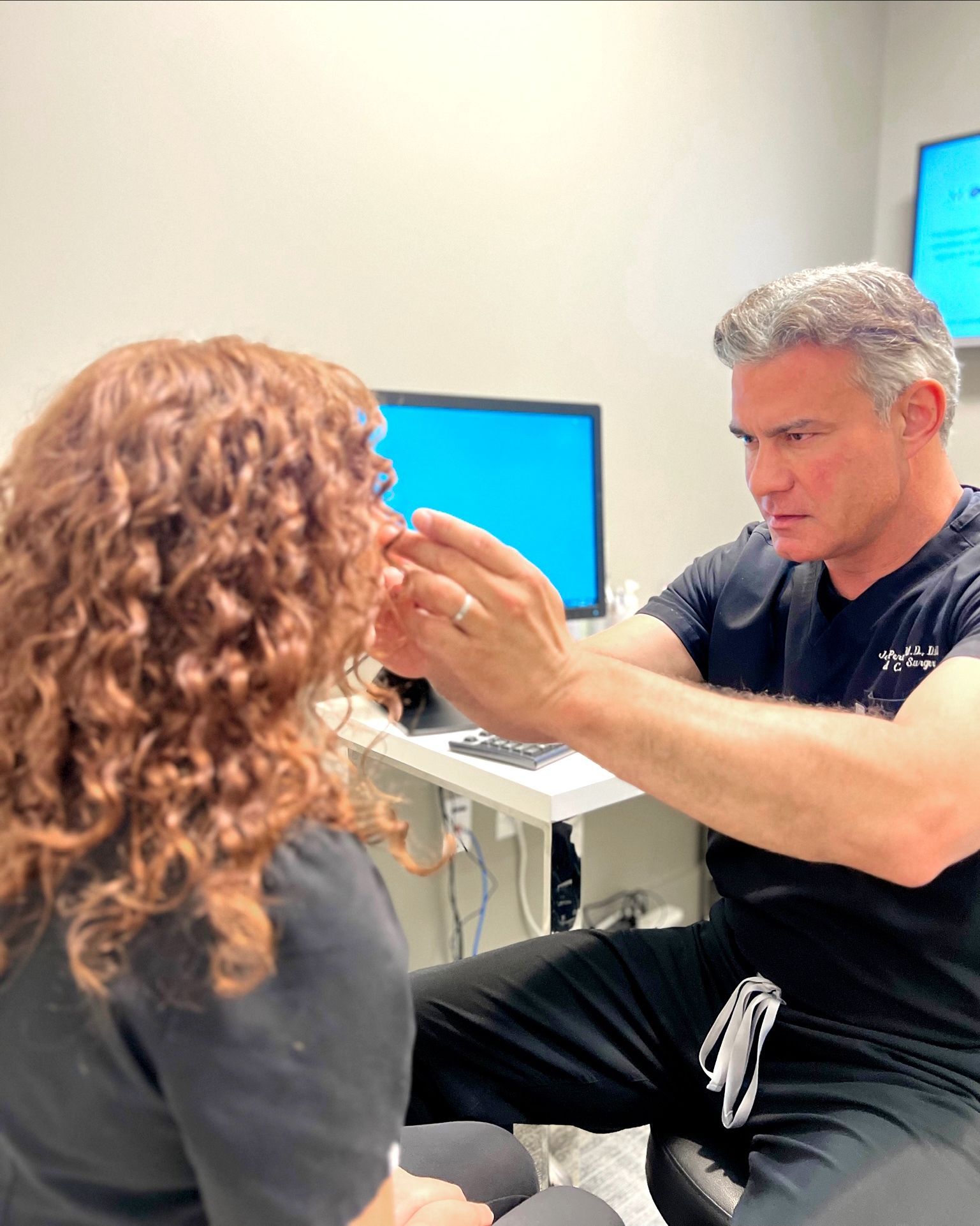 A doctor examines a patient's ear in an office setting.