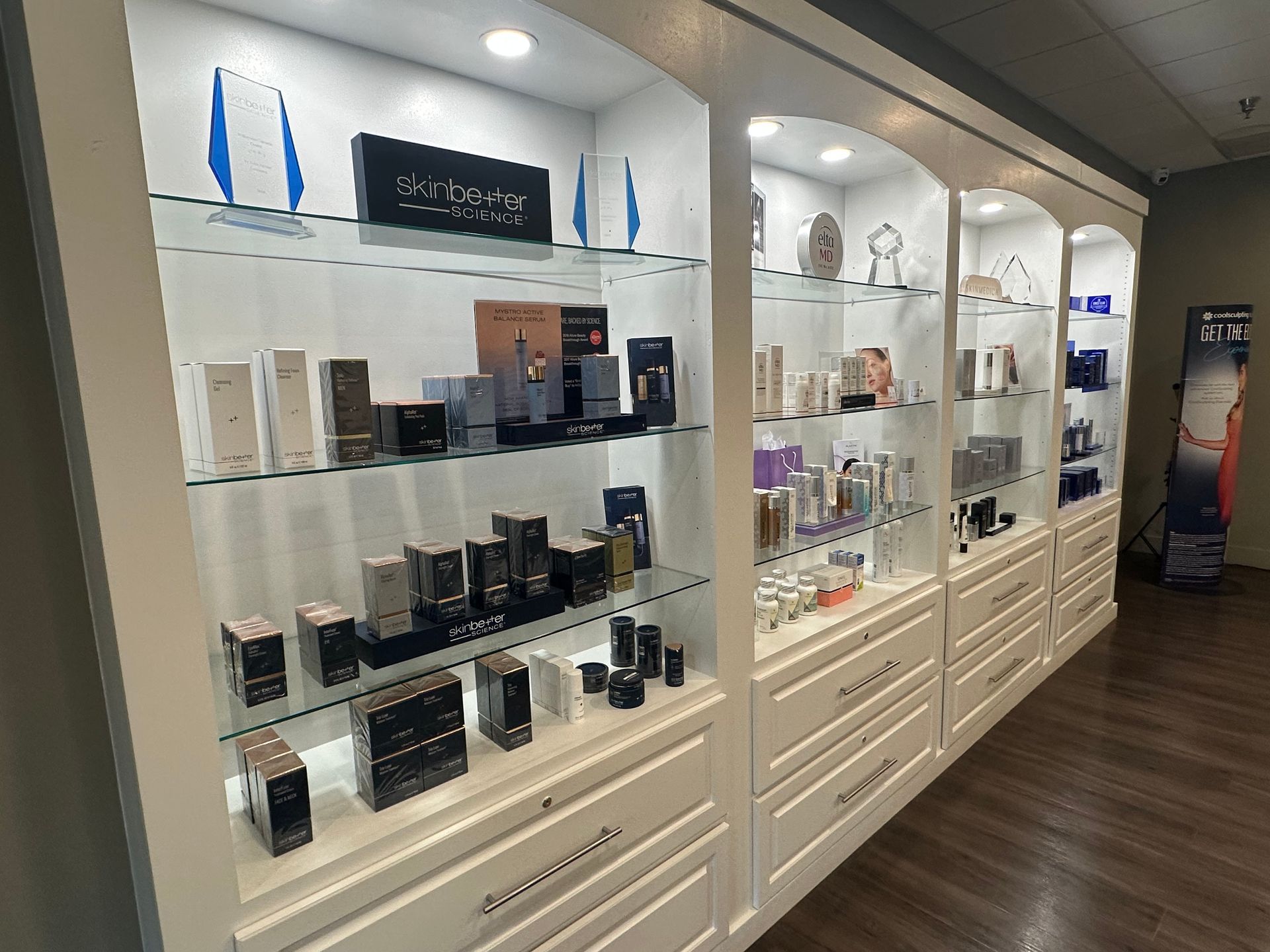 White display cabinets showcasing beauty products in a well-lit store setting.