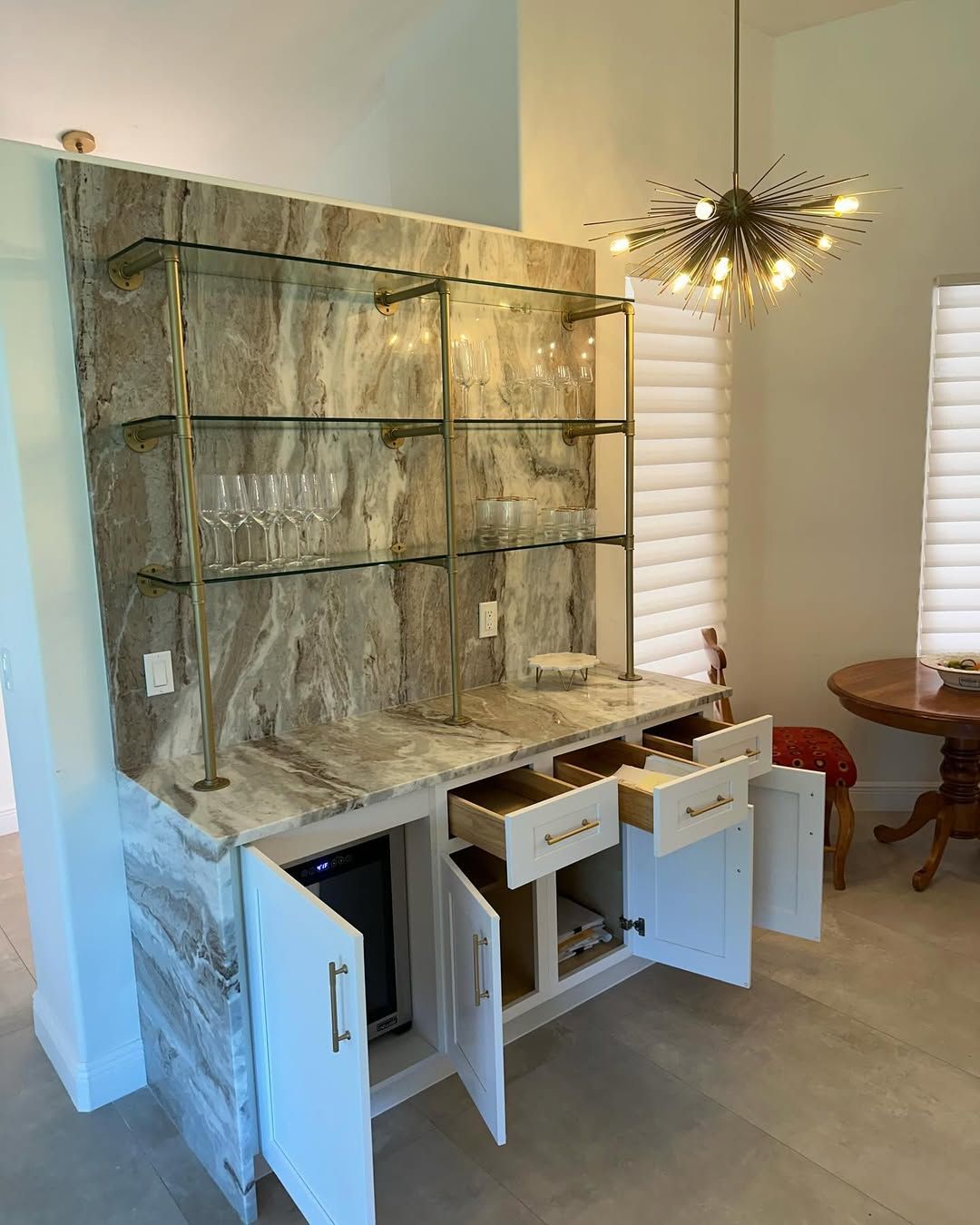 White hutch cabinet with open drawers and doors in a bright dining room