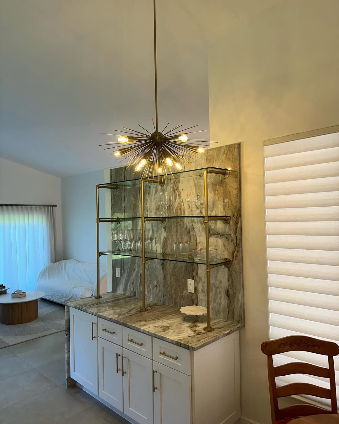 Glass cabinet with decorative branches and lights in a bedroom, beside a white window blind