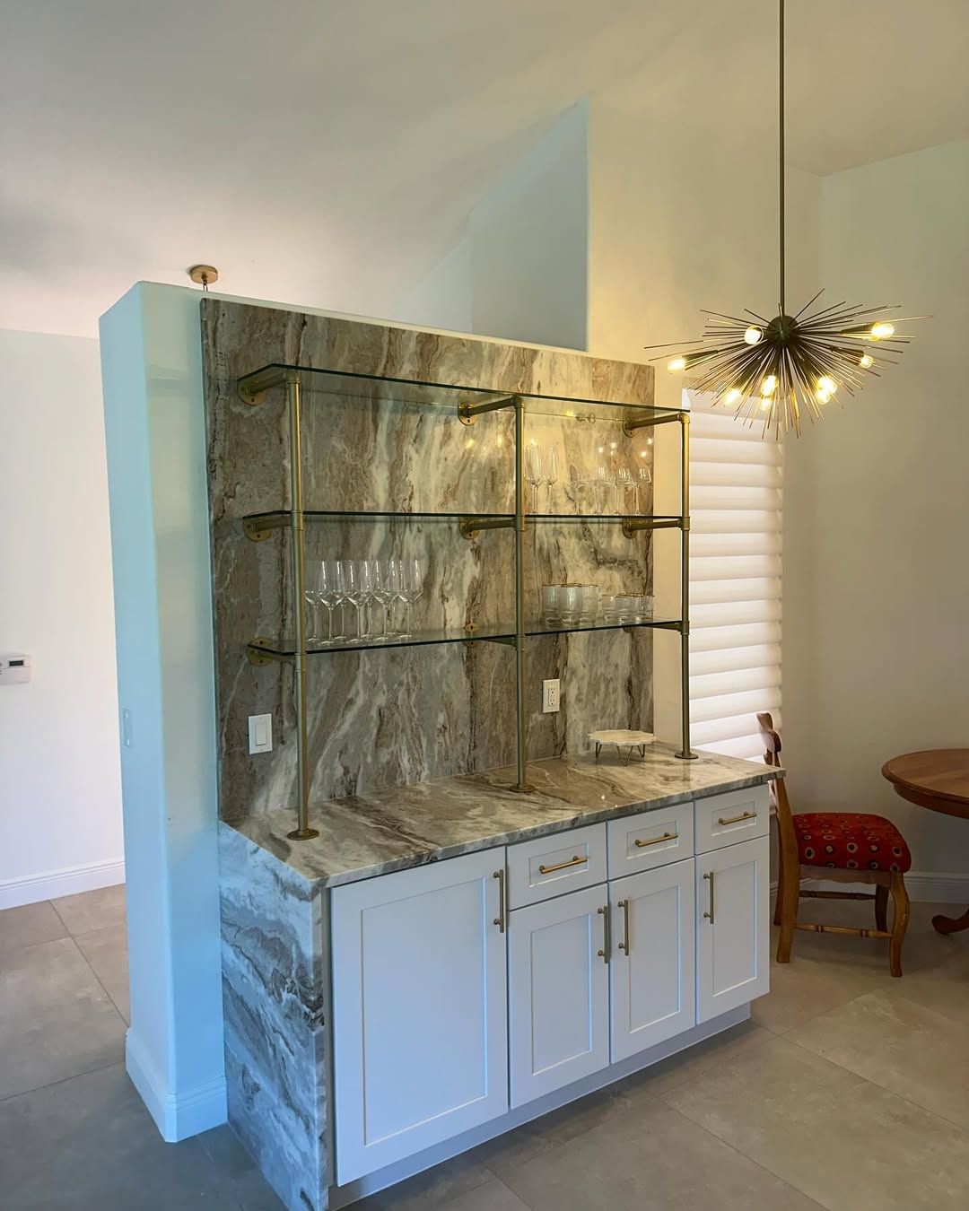Built-in stone display shelves above white cabinets in a bright dining room