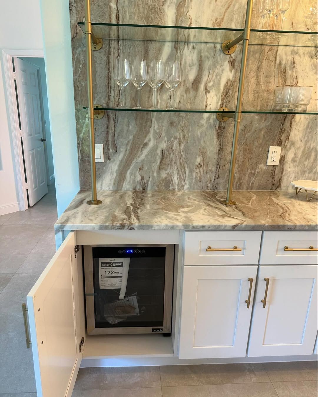 Modern kitchen with marble backsplash, white cabinets, and a built-in wine cooler.