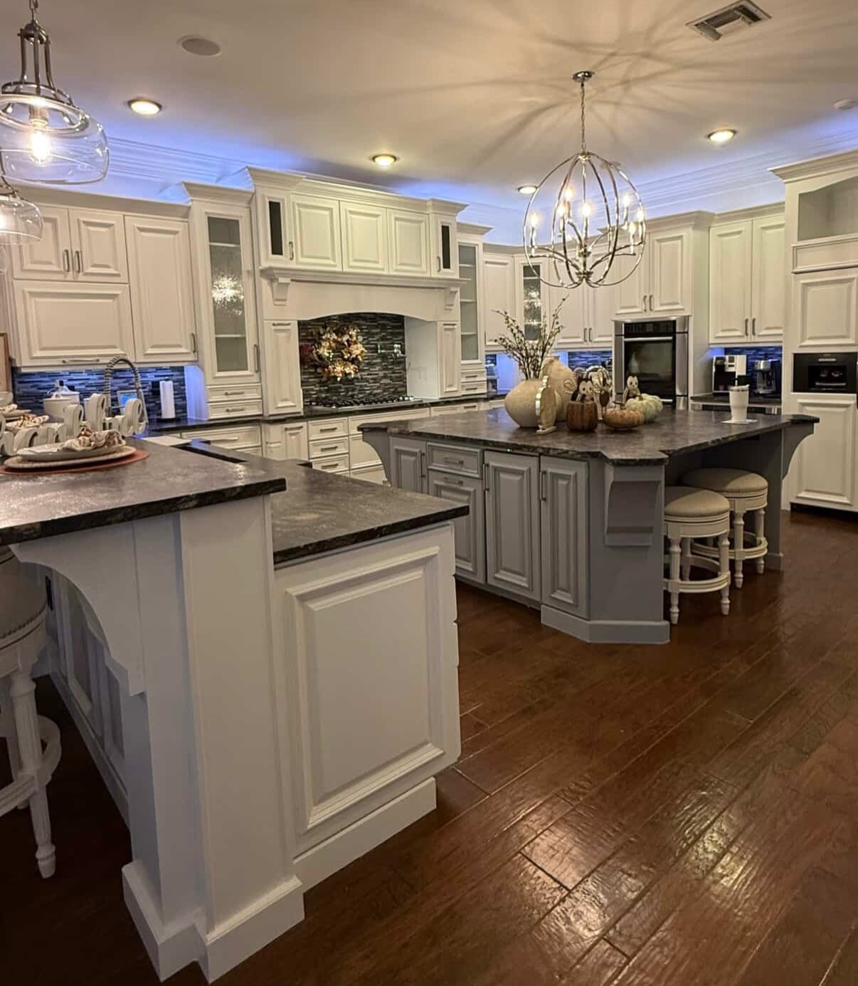 Bright white kitchen with dark counters, island seating, pendant lights, and wood floors