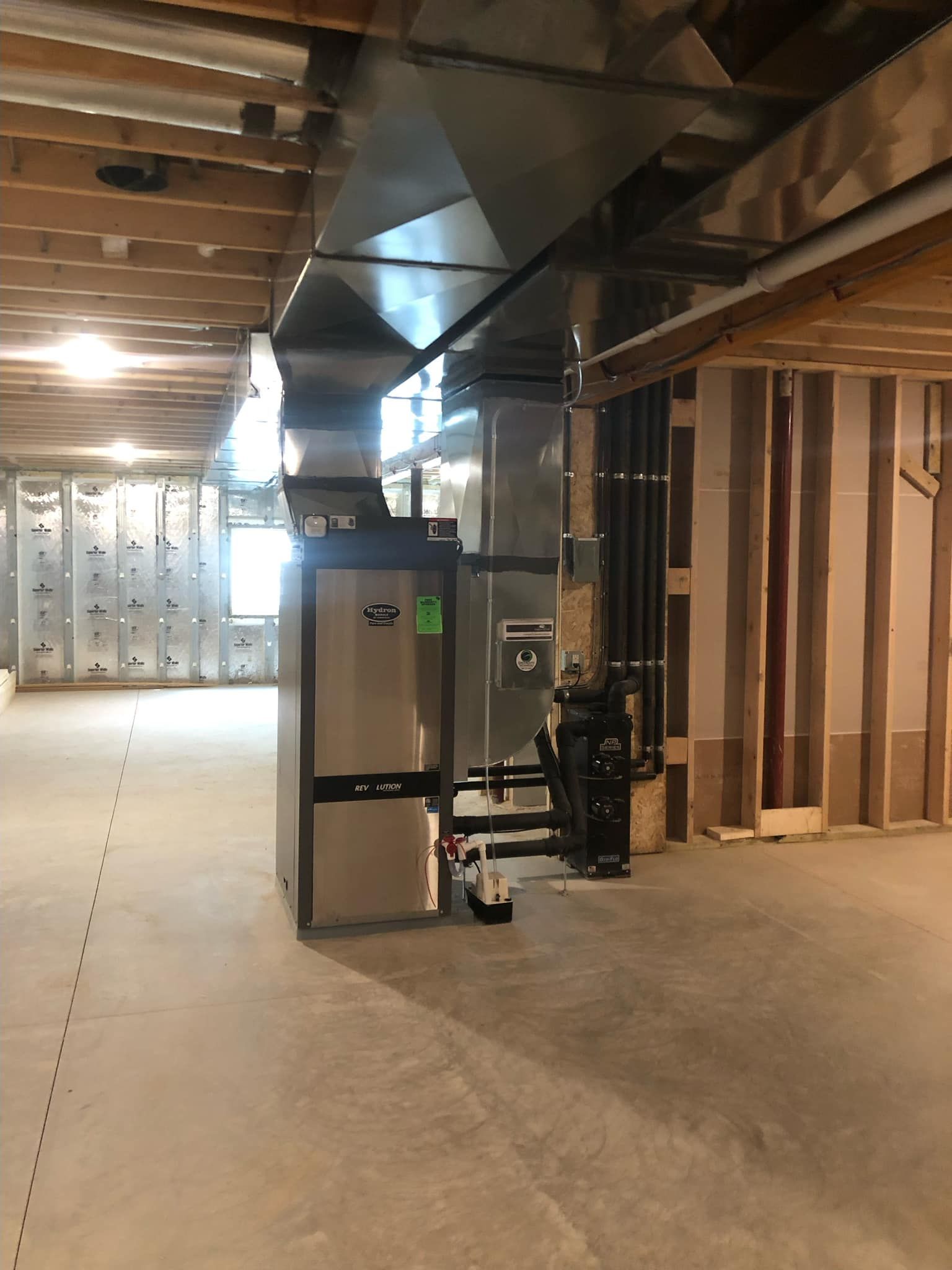 HVAC system in a basement. Furnace, ductwork, and pipes installed against unfinished walls.