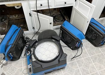 A bunch of blue and black appliances are sitting on the floor in a kitchen.