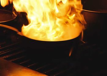 A pan of food is being cooked on a grill with flames coming out of it.