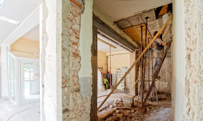 A man is standing on a ladder in a building under construction.