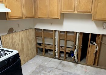 A kitchen with wooden cabinets , a stove , and a sink.