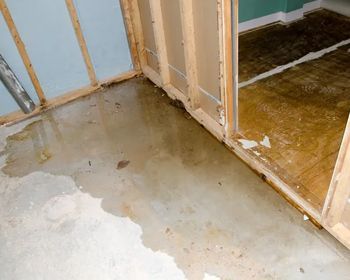 A fireman is standing on top of a ladder on the roof of a house.