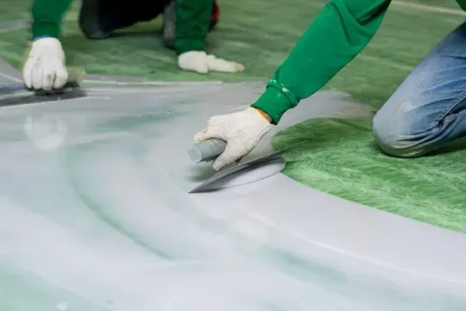 Professional contractors applying a smooth epoxy floor coating with trowels.