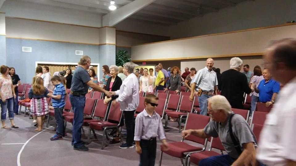 A group of people are standing in a church talking to each other