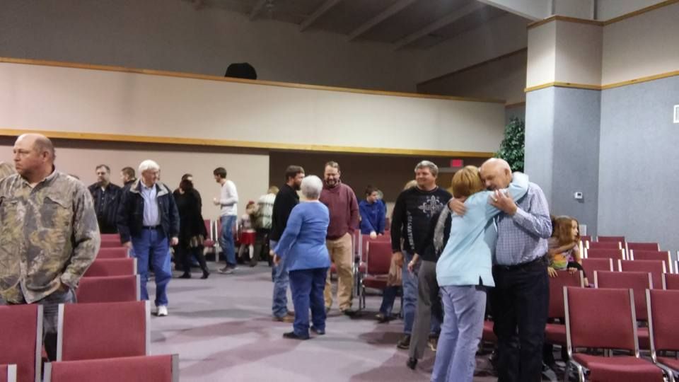 A group of people standing in a room with red chairs