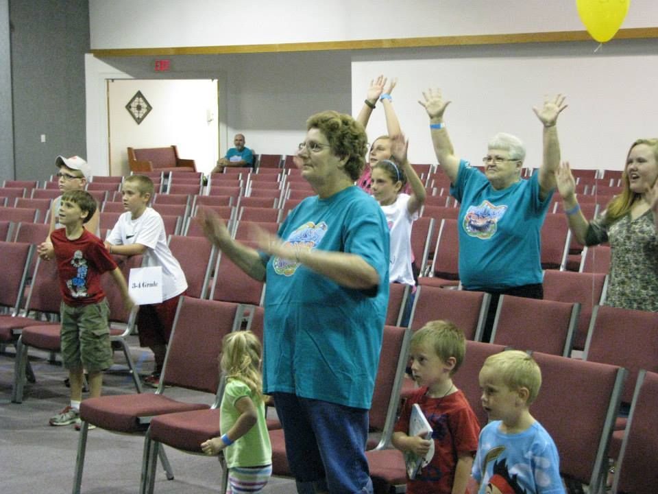 A group of people are standing in a room with their hands in the air