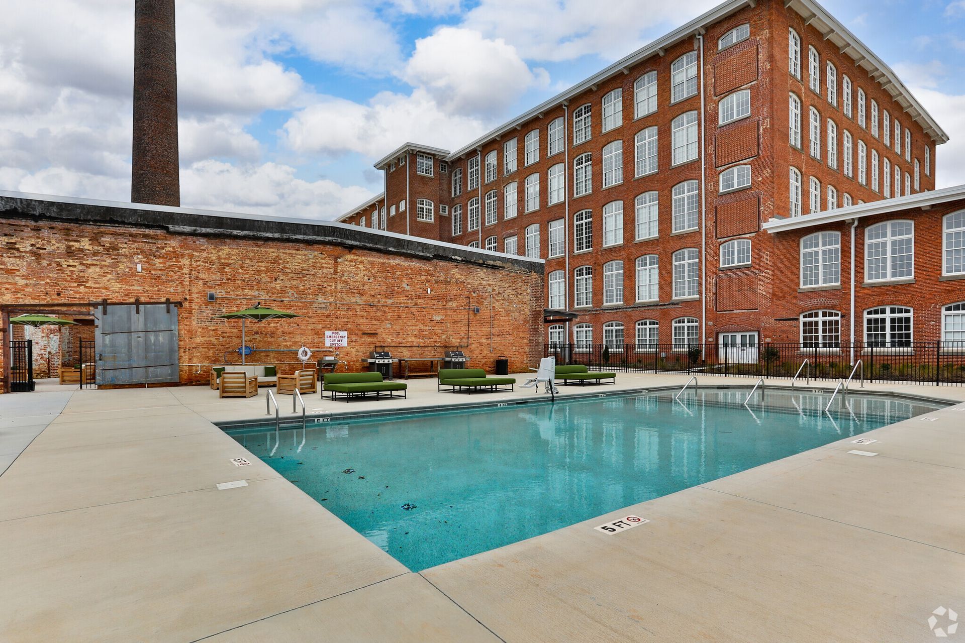 A large swimming pool in front of a large brick building.